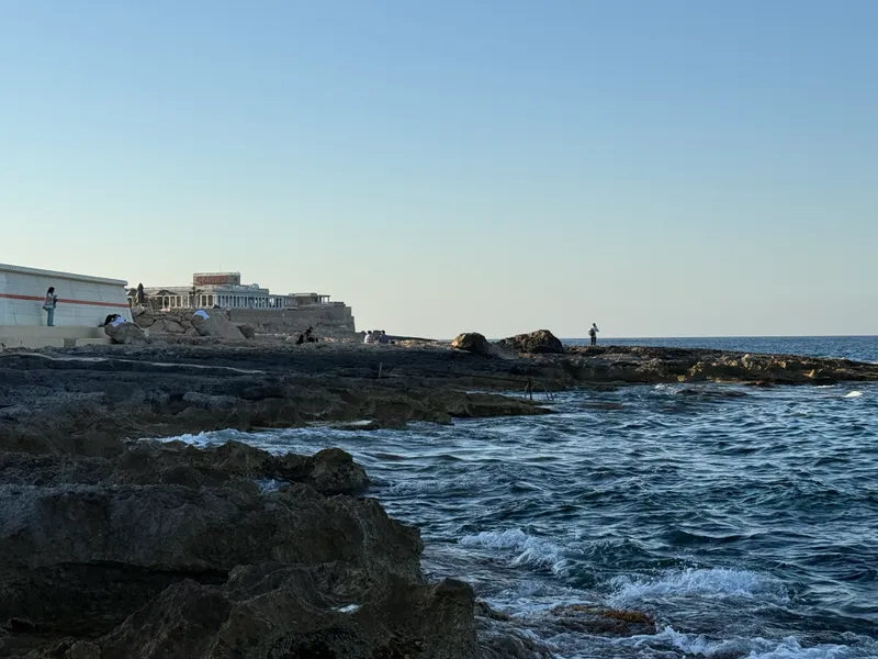 The rocks side of the argument: the rocky point behind Paceville on a July evening, swimmers still in the water