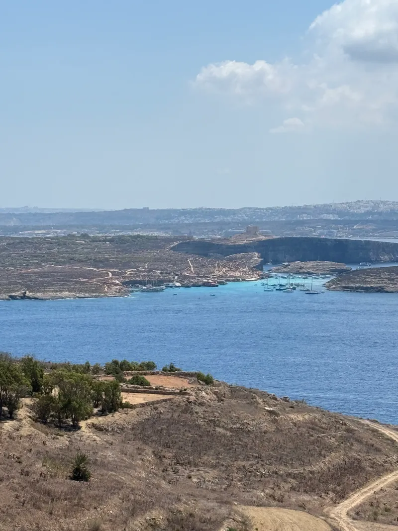 The channel from the hills above Qala: Comino and the Blue Lagoon in front, Malta behind. Every ferry to Gozo crosses this stretch of water.